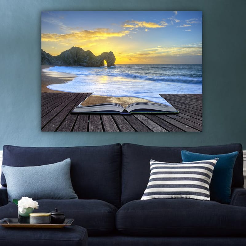 Lerretsbilde 70x100 cm - Åpen bok liggende på en trebrygge med en solnedgang ved havet i bakgrunnen - Blå / Oransje / Beige - Innredning - Bilder & kunst - Lerretsbilder