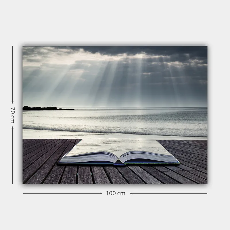 Lerretsbilde 70x100 cm - Åpen bok liggende på en trebrygge ved sjøen, omgitt av myke lysstråler fra en overskyet himmel - Grå / Blå / Hvit - Innredning - Bilder & kunst - Lerretsbilder