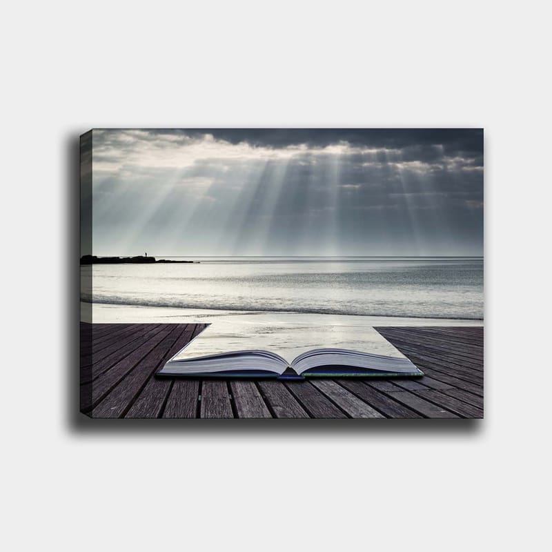 Lerretsbilde 70x100 cm - Åpen bok liggende på en trebrygge ved sjøen, omgitt av myke lysstråler fra en overskyet himmel, Grå / Blå / Hvit