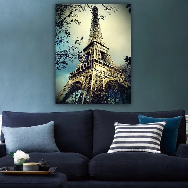 Lerretsbilde 70x100 cm - Eiffeltårnet i Paris, fotografert fra lav vinkel med omkringliggende tregrener - Grå / Beige / Blå - Innredning - Bilder & kunst - Lerretsbilder