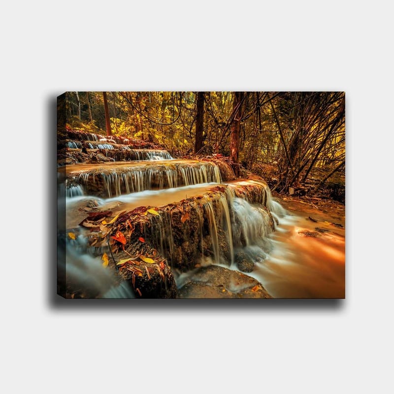 Lerretsbilde 70x100 cm - En vakker foss som renner ned flere nivåer i en høstfarget skog, Gull / Brun / Oransje