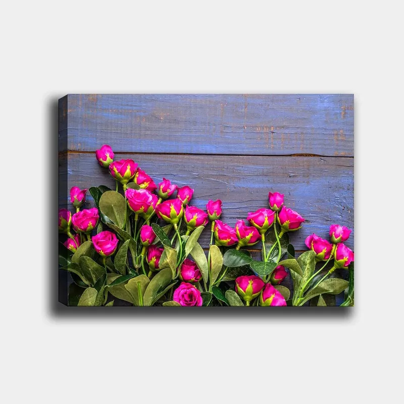 Lerretsbilde 70x100 cm - Fargerik samling av rosa roser mot en blå trebakgrunn, Rosa / Grønn / Blå
