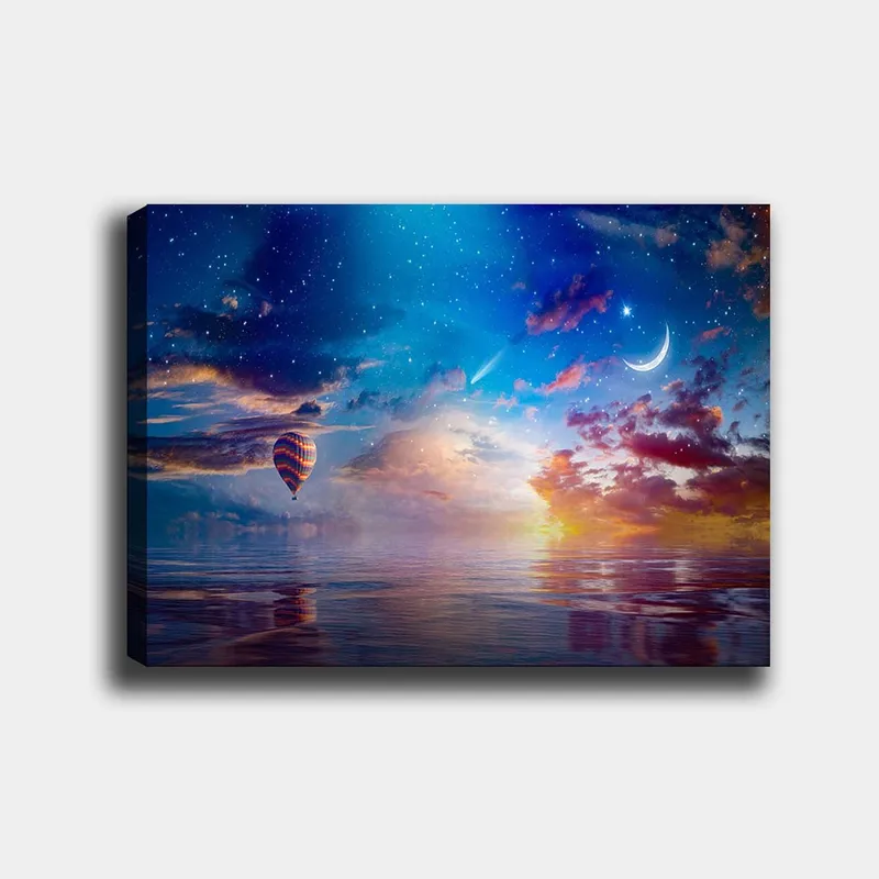 Lerretsbilde 70x100 cm - Fargerik varmluftsballong svever over en speillignende overflate under en stjernehimmel med dramatiske skyer og en måne, Blå / Oransje / Rød