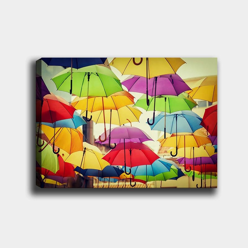 Lerretsbilde 70x100 cm - Fargerike paraplyer som henger i luften skaper en livlig og leken atmosfære, Grønn / Gul / Rød