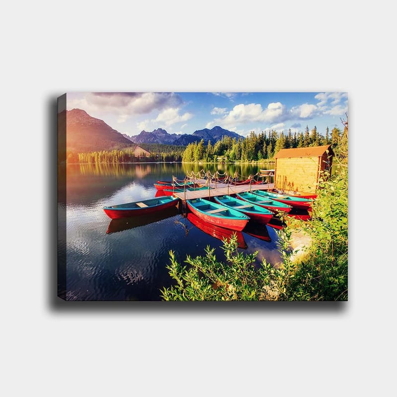 Lerretsbilde 70x100 cm - Flere fargerike båter ligger på en speilblank innsjø omgitt av frodige trær og fjell, Rød / Turkis / Grønn