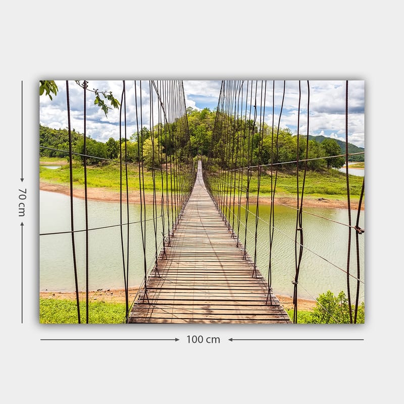 Lerretsbilde 70x100 cm - Hengebro som går over en rolig innsjø, omgitt av frodig grøntområde - Grønn / Brun / Blå - Innredning - Bilder & kunst - Lerretsbilder