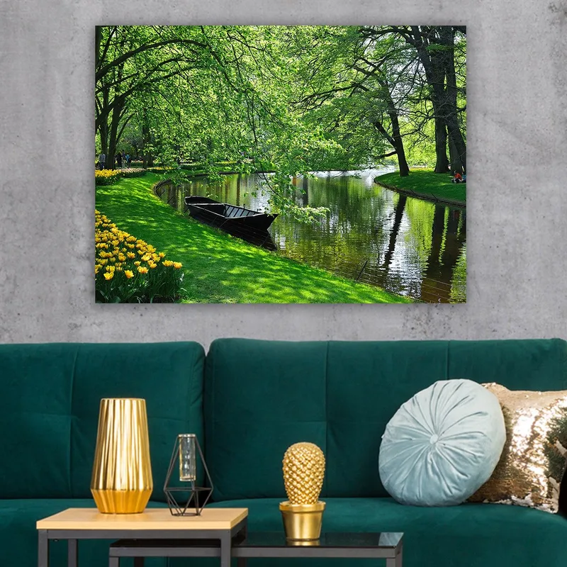Lerretsbilde 70x100 cm - Idyllisk innsjø med en båt som ligger stille på en grønn strand omgitt av trær og blomster - Grønn / Svart / Gul - Innredning - Bilder & kunst - Lerretsbilder