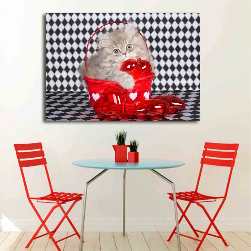 Lerretsbilde 70x100 cm - Kattunge sitter i en rød kurv fylt med hjerteformede dekorasjoner - Rød / Grå - Innredning - Bilder & kunst - Lerretsbilder