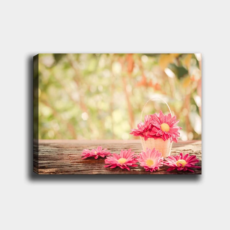 Lerretsbilde 70x100 cm - Kurv fylt med rosa blomster på en treflate, Rosa / Gul / Brun