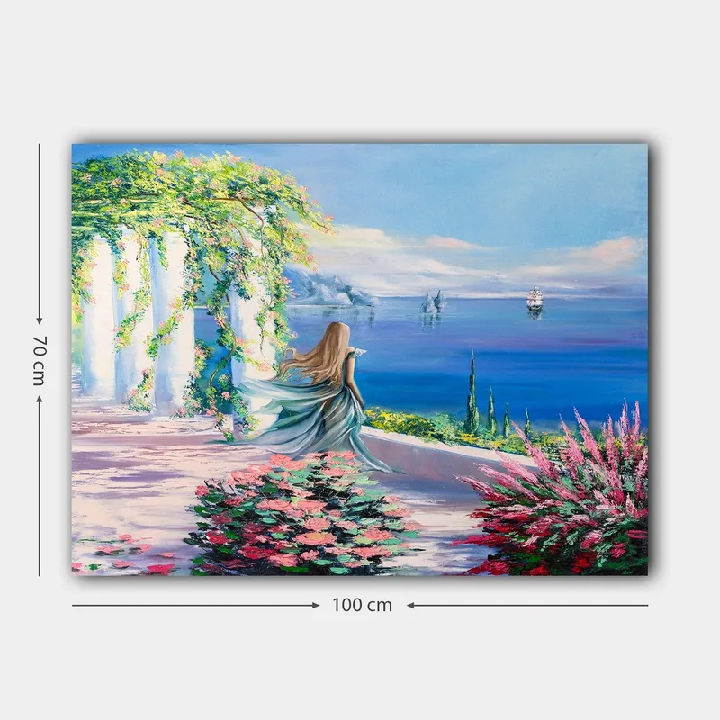 Lerretsbilde 70x100 cm - Kvinne i blå kjole som står ved et utsiktspunkt med havet og seilbåter i bakgrunnen - Blå / Grønn / Rosa - Innredning - Bilder & kunst - Lerretsbilder
