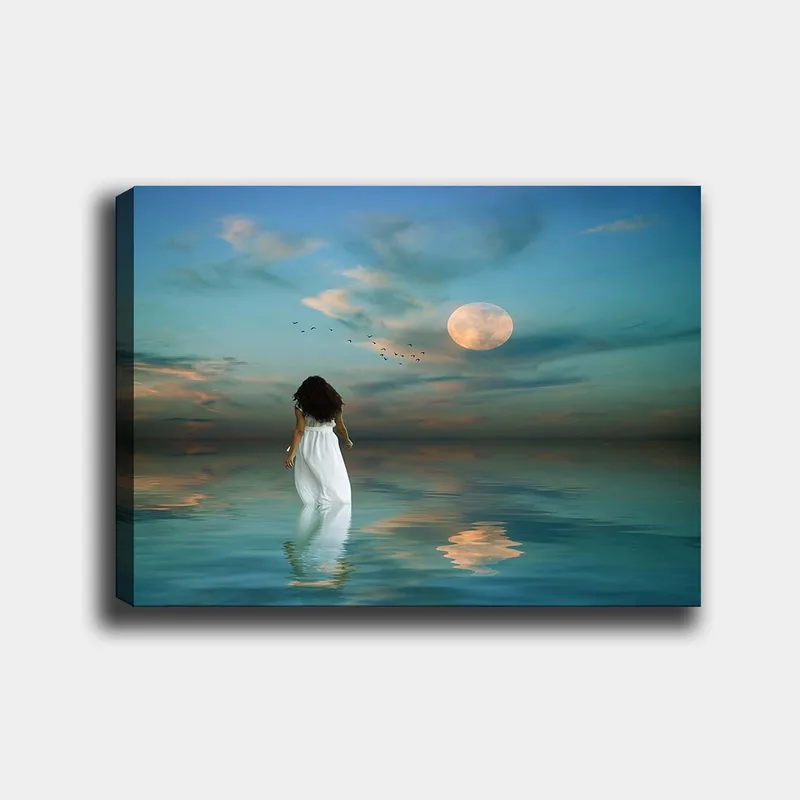 Lerretsbilde 70x100 cm - Kvinne i hvit kjole går gjennom et speilblankt hav under en stjernehimmel med en stor måne, Blå / Hvit / Grå