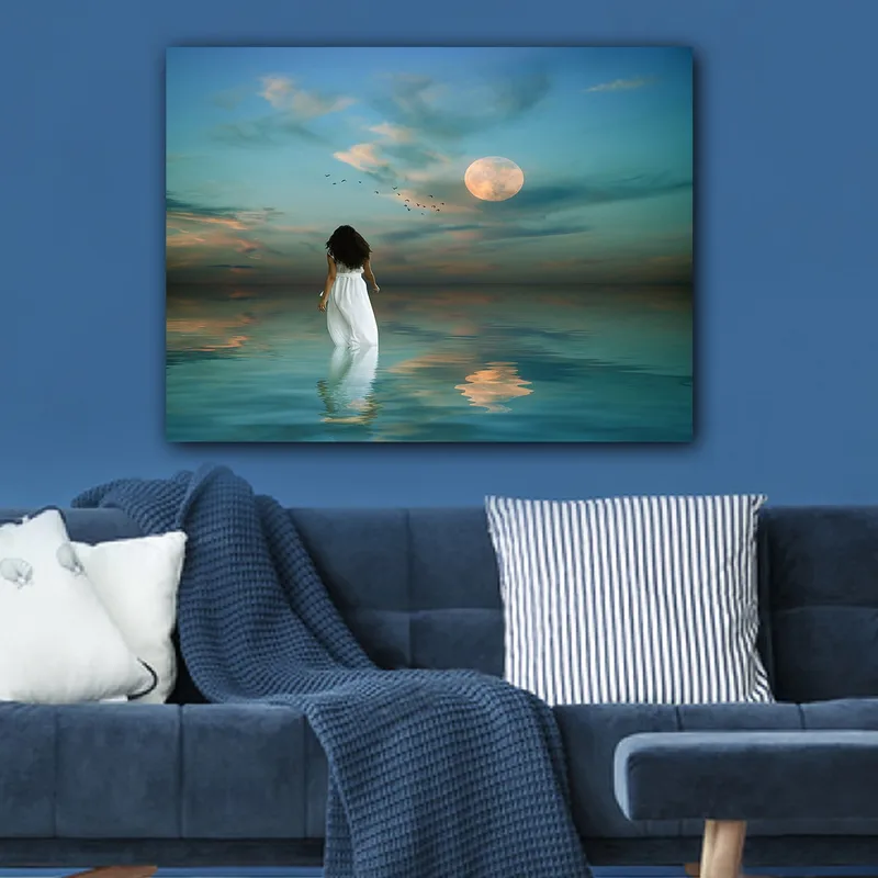 Lerretsbilde 70x100 cm - Kvinne i hvit kjole går gjennom et speilblankt hav under en stjernehimmel med en stor måne - Blå / Hvit / Grå - Innredning - Bilder & kunst - Lerretsbilder