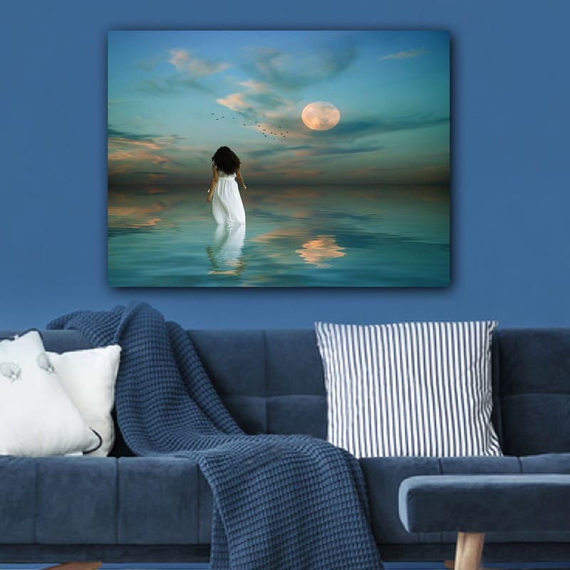 Lerretsbilde 70x100 cm - Kvinne i hvit kjole går gjennom et speilblankt hav under en stjernehimmel med en stor måne - Blå / Hvit / Grå - Innredning - Bilder & kunst - Lerretsbilder