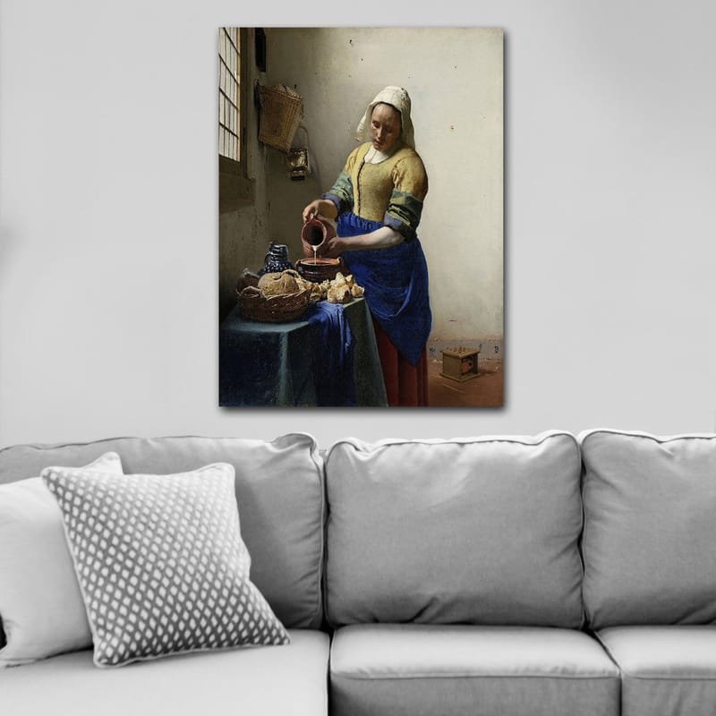 Lerretsbilde 70x100 cm - Kvinne som heller melk i en bolle på et lyst kjøkken - Blå / Gul / Brun - Innredning - Bilder & kunst - Lerretsbilder