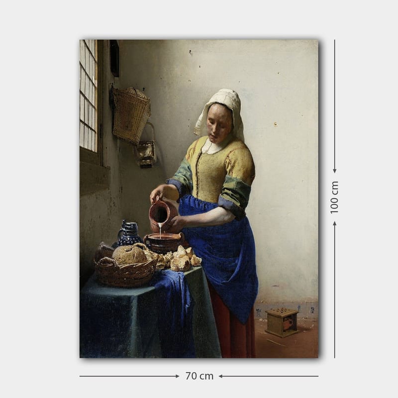 Lerretsbilde 70x100 cm - Kvinne som heller melk i en bolle på et lyst kjøkken - Blå / Gul / Brun - Innredning - Bilder & kunst - Lerretsbilder