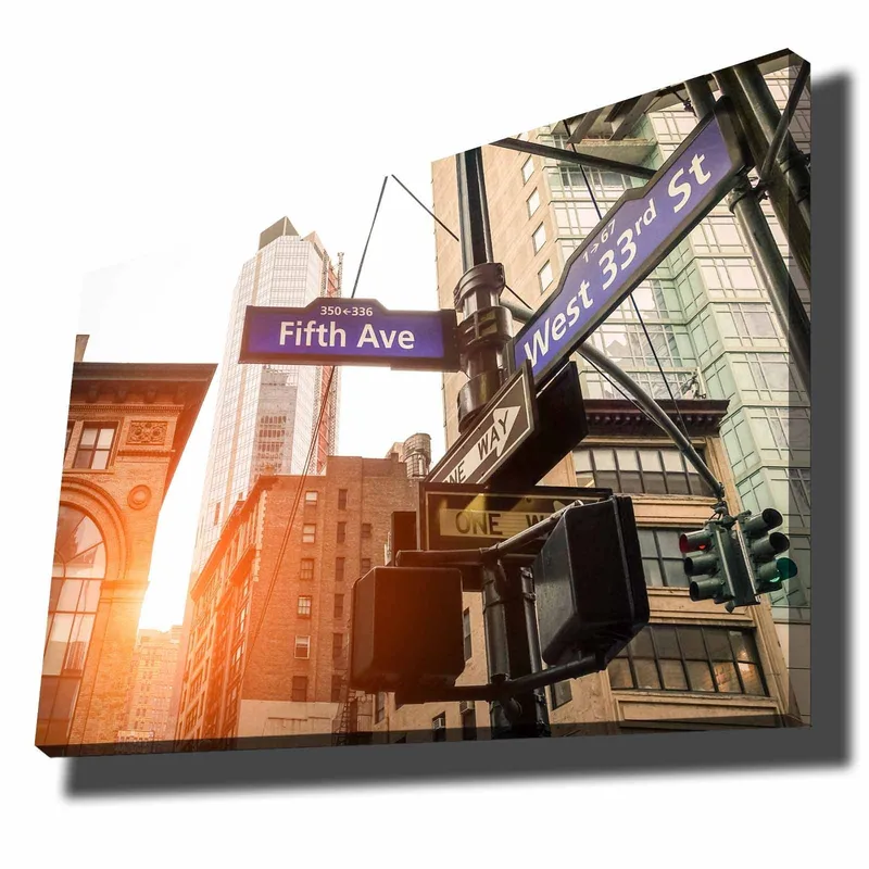 Lerretsbilde 70x100 cm - Livlig bybilde med veiskilt i et kryss i en storby, Blå / Brun / Grønn