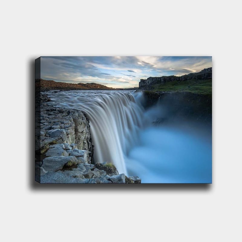 Lerretsbilde 70x100 cm - Majestetisk foss som renner over steiner i naturskjønne omgivelser, Blå / Grå / Hvit