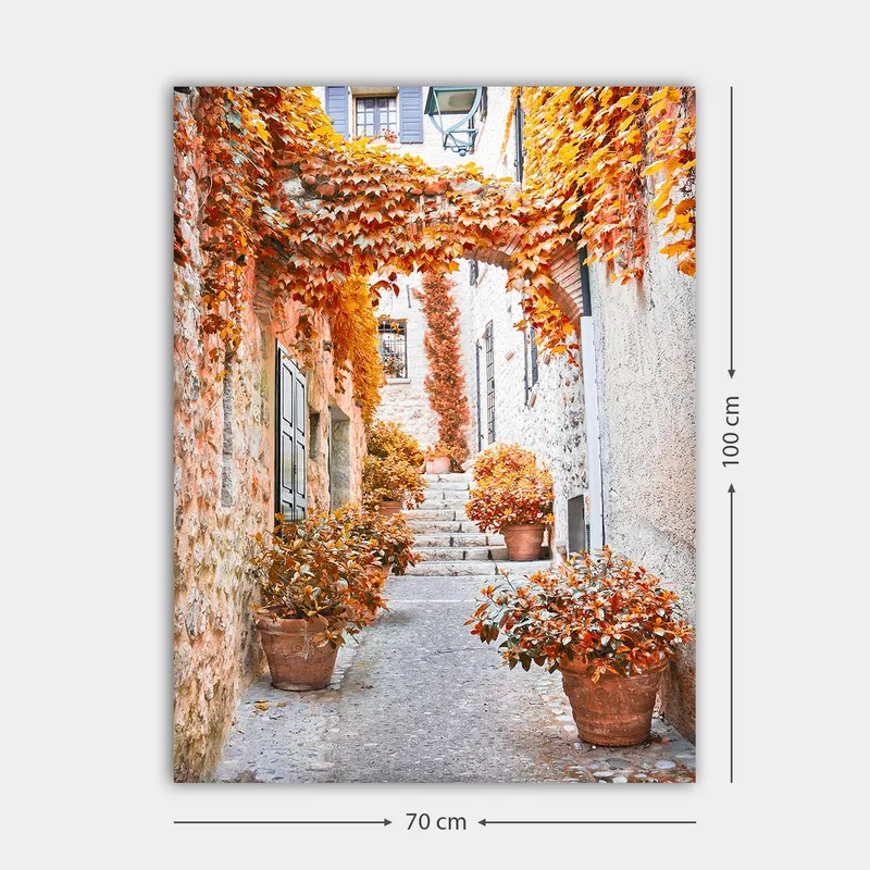 Lerretsbilde 70x100 cm - Malerisk smug omgitt av fargerike høstblader og potteplanter - Oransje / Brun / Gul - Innredning - Bilder & kunst - Lerretsbilder