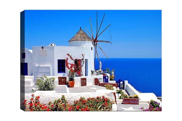 Lerretsbilde 70x100 cm - Malerisk utsikt over en hvitkalket bygning med en tradisjonell vindmølle og fargerike blomster på Santorini - Hvit / Blå / Rød - Innredning - Bilder & kunst - Lerretsbilder