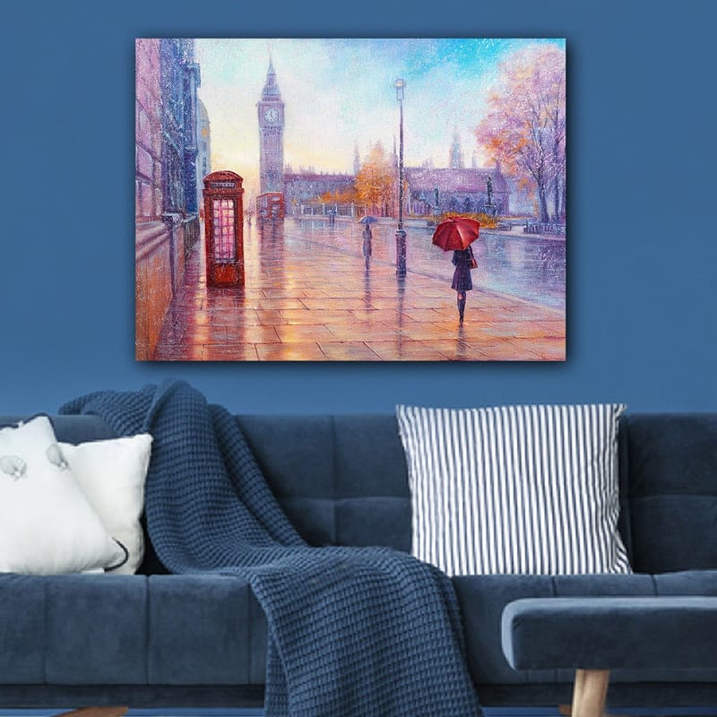 Lerretsbilde 70x100 cm - Regnfullt bybilde med en rød telefonkiosk og en person med en rød paraply som går langs en våt gate - Rød / Blå / Oransje - Innredning - Bilder & kunst - Lerretsbilder