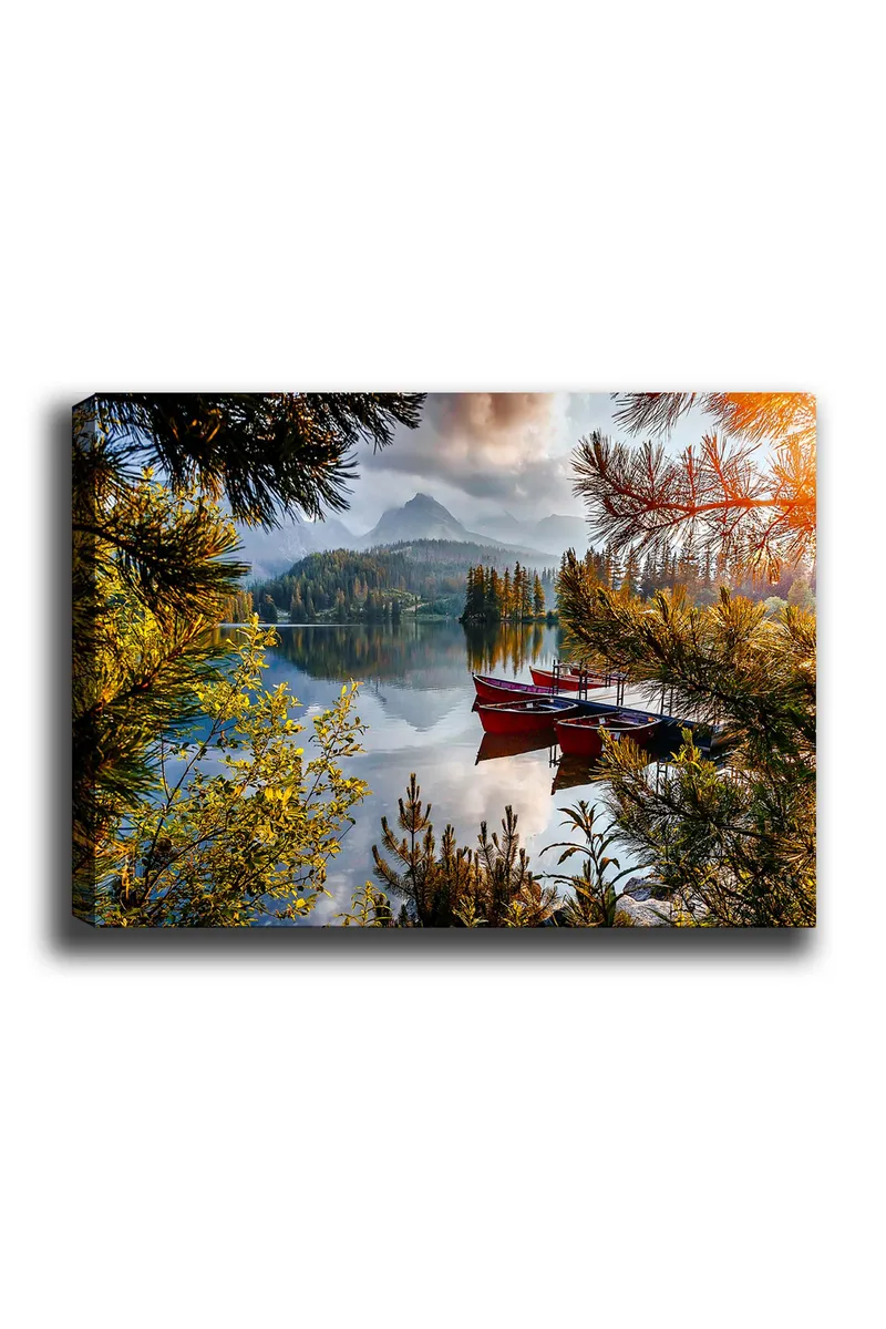 Lerretsbilde 70x100 cm - Rolig innsjø med en rød båt ved en trebrygge, omgitt av frodige trær og fjerne fjell, Grønn / Rød / Blå