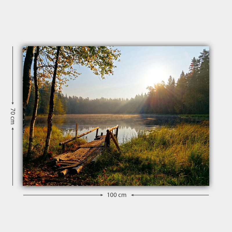 Lerretsbilde 70x100 cm - Rolig innsjø med en trebro omgitt av frodige trær og morgensolens stråler - Grønn / Brun / Gul - Innredning - Bilder & kunst - Lerretsbilder