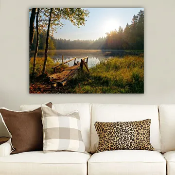 Lerretsbilde 70x100 cm - Rolig innsjø med en trebro omgitt av frodige trær og morgensolens stråler - Grønn / Brun / Gul - Innredning - Bilder & kunst - Lerretsbilder