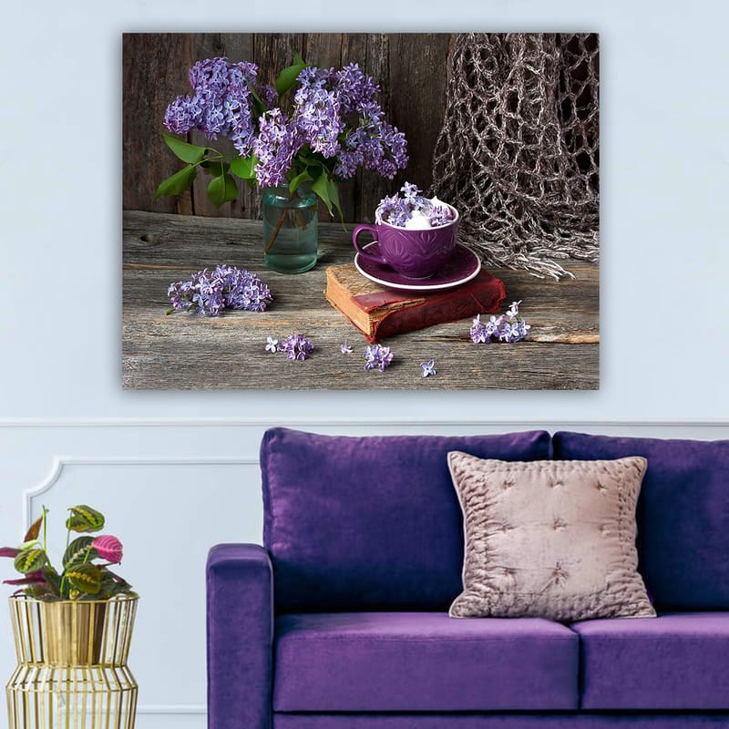 Lerretsbilde 70x100 cm - Rolig naturmaleri med lilla syriner i en glassvase og en lilla kopp på en gammel bok, Lilla / Grønn / Brun