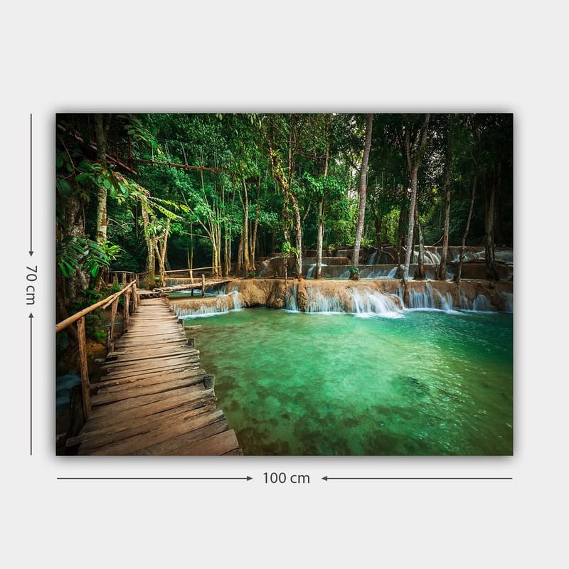 Lerretsbilde 70x100 cm - Rolig og naturskjønt sted med en trebro som fører over et klart, turkis fossefallbasseng omgitt av frodig grøntområde - Turkis / Grønn / Brun - Innredning - Bilder & kunst - Lerretsbilder