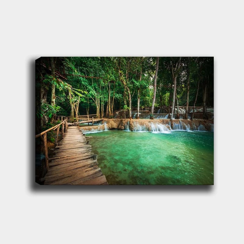 Lerretsbilde 70x100 cm - Rolig og naturskjønt sted med en trebro som fører over et klart, turkis fossefallbasseng omgitt av frodig grøntområde, Turkis / Grønn / Brun
