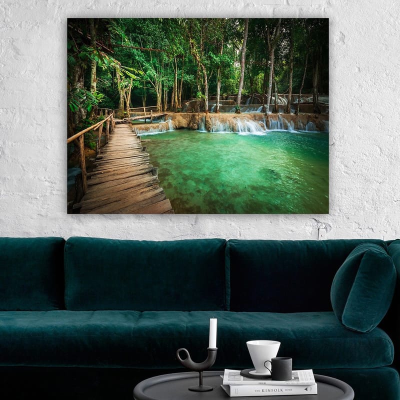 Lerretsbilde 70x100 cm - Rolig og naturskjønt sted med en trebro som fører over et klart, turkis fossefallbasseng omgitt av frodig grøntområde - Turkis / Grønn / Brun - Innredning - Bilder & kunst - Lerretsbilder