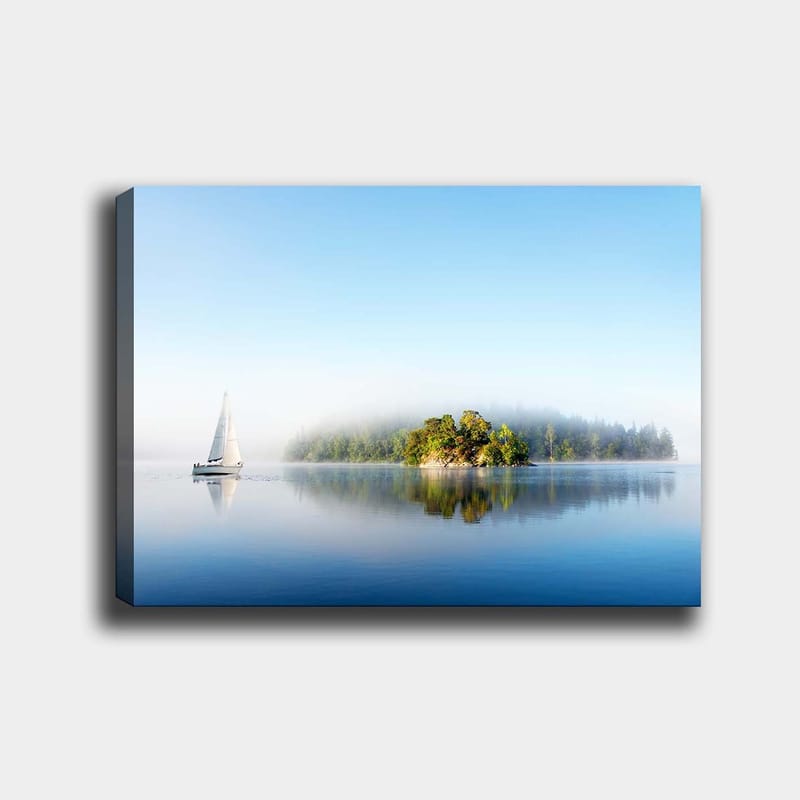 Lerretsbilde 70x100 cm - Seilbåt glir over en speilblank innsjø med en tåkete øy i bakgrunnen, Blå / Grønn / Hvit