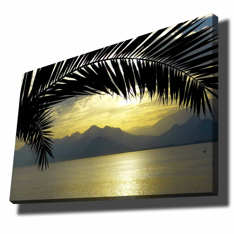 Lerretsbilde 70x100 cm - Silhuett av palmer mot en gyllen solnedgang over fjellene og havet, Svart / Gull / Grå