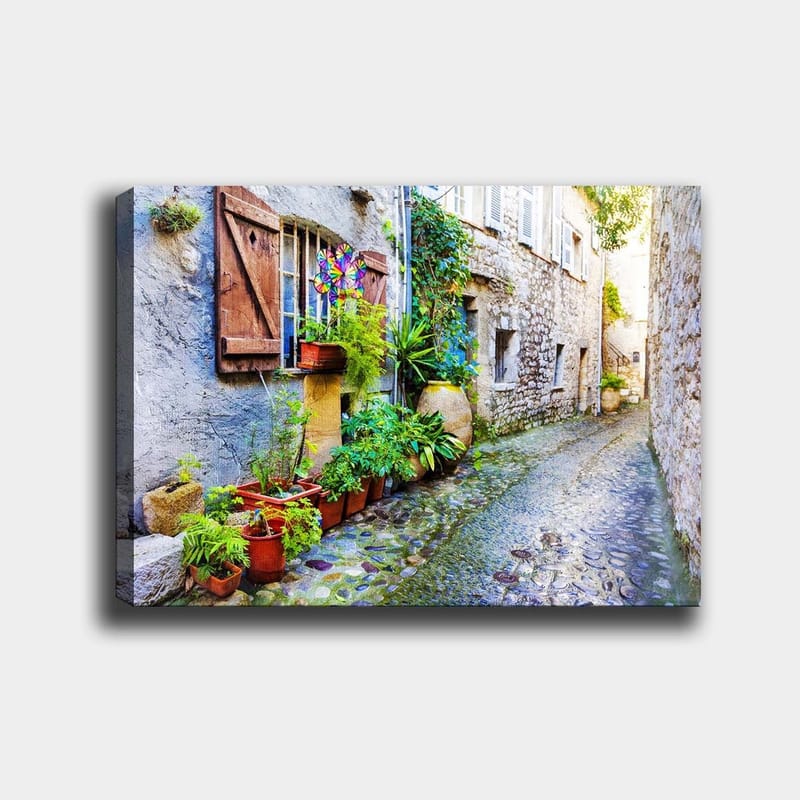 Lerretsbilde 70x100 cm - Sjarmerende smug med steinhus og blomsterpotter som skaper en livlig atmosfære - Grønn / Blå / Beige - Innredning - Bilder & kunst - Lerretsbilder