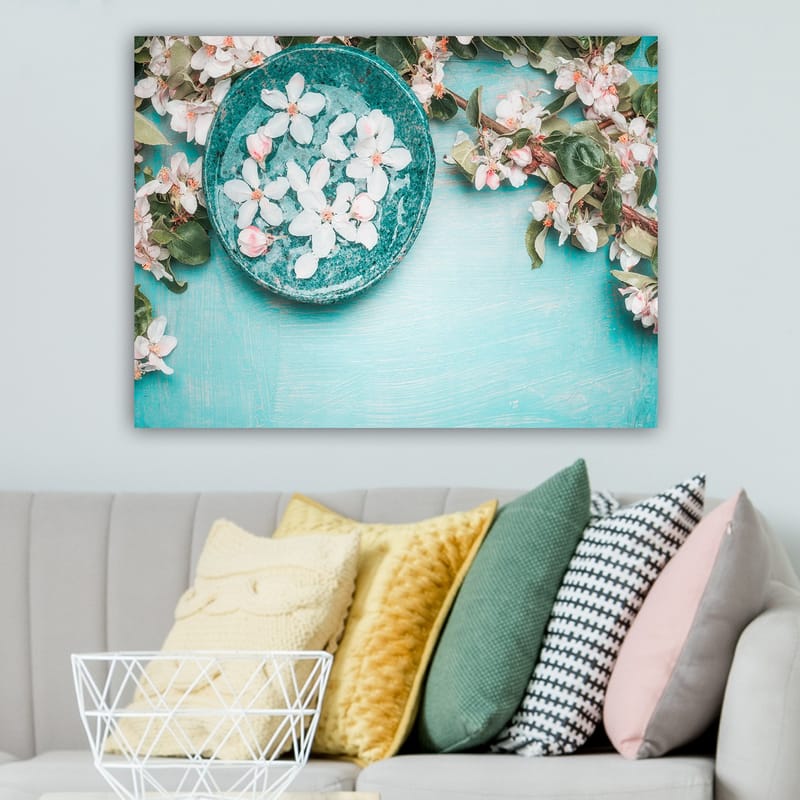 Lerretsbilde 70x100 cm - Skål med blomster omgitt av frodige grønne kvister og blomster på en lyseblå bakgrunn - Turkis / Hvit / Rosa - Innredning - Bilder & kunst - Lerretsbilder
