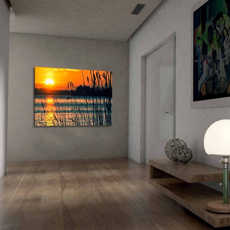 Lerretsbilde 70x100 cm - Solnedgang over en rolig vannflate med gress som svaier i vinden - Oransje / Blå / Svart - Innredning - Bilder & kunst - Lerretsbilder
