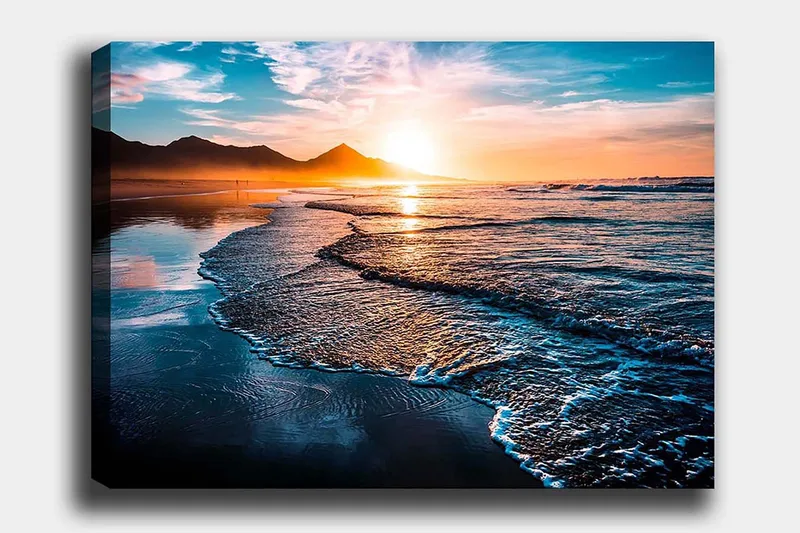 Lerretsbilde 70x100 cm - Solnedgang over en strand med milde bølger som ruller inn mot kysten, Blå / Oransje / Turkis