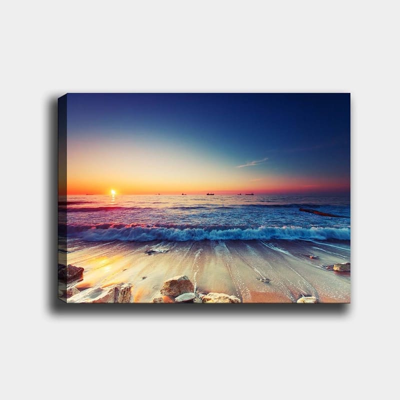 Lerretsbilde 70x100 cm - Solnedgang over havet med myke bølger som ruller inn mot kysten - Blå / Oransje / Rosa - Innredning - Bilder & kunst - Lerretsbilder