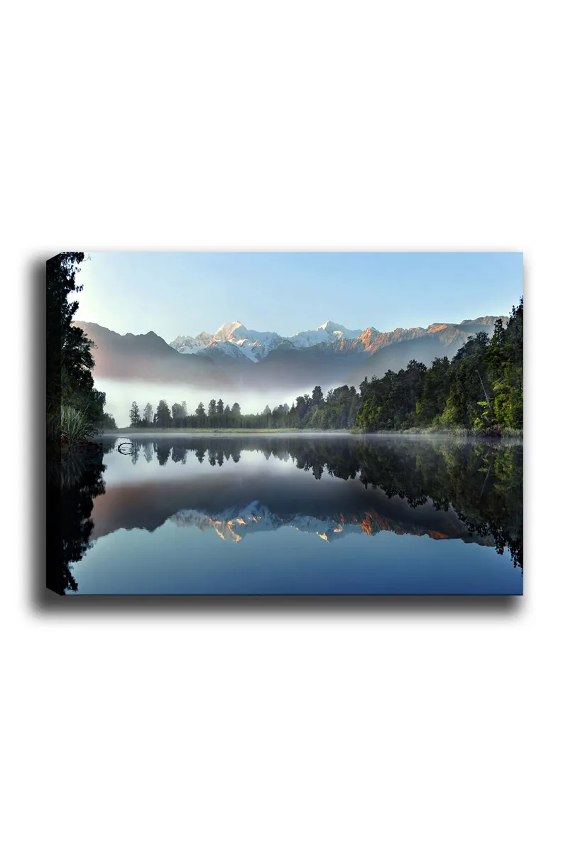 Lerretsbilde 70x100 cm - Speilbilde av majestetiske fjell speilet i en rolig innsjø omgitt av frodig skog, Blå / Grønn / Hvit