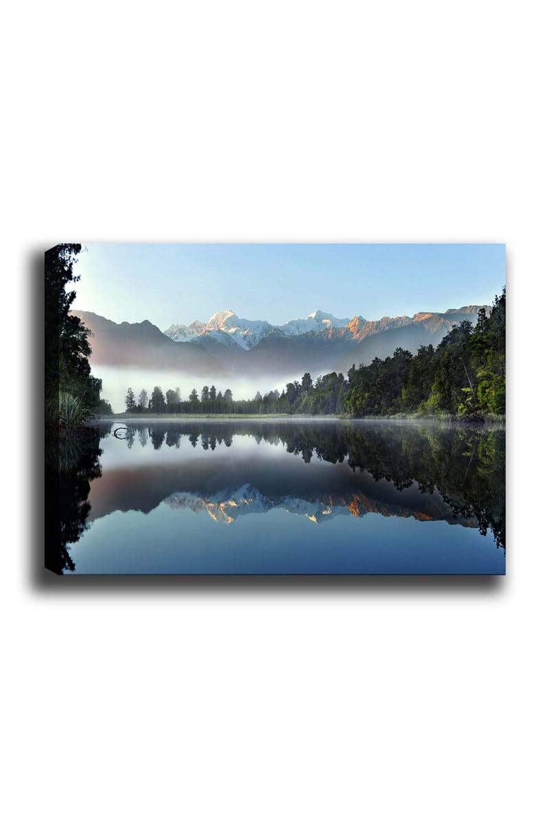 Lerretsbilde 70x100 cm - Speilbilde av majestetiske fjell speilet i en rolig innsjø omgitt av frodig skog, Blå / Grønn / Hvit