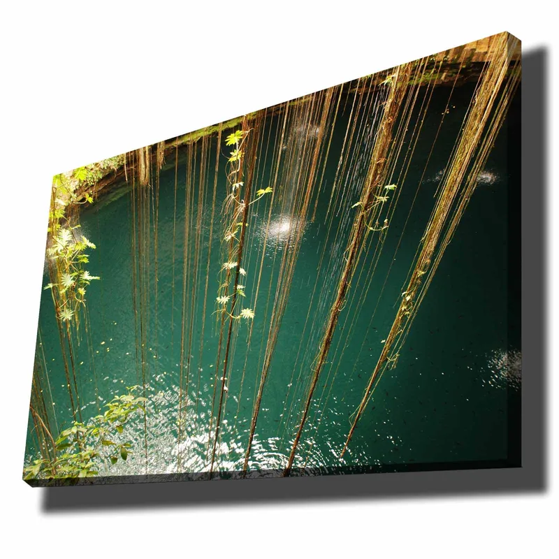 Lerretsbilde 70x100 cm - Stille vannflate omgitt av hengende vegetasjon og naturlige elementer, Turkis / Grønn / Brun