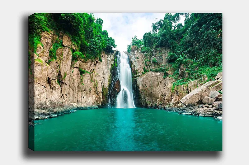 Lerretsbilde 70x100 cm - Storslått foss som fosser ned i en klar, turkis innsjø omgitt av frodige, grønne klipper - Turkis / Grønn / Beige - Innredning - Bilder & kunst - Lerretsbilder