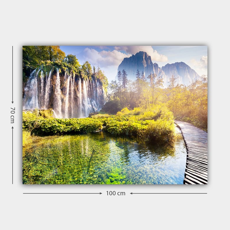 Lerretsbilde 70x100 cm - Storslått fossefall omgitt av frodig vegetasjon og majestetiske fjell - Grønn / Blå / Gul - Innredning - Bilder & kunst - Lerretsbilder