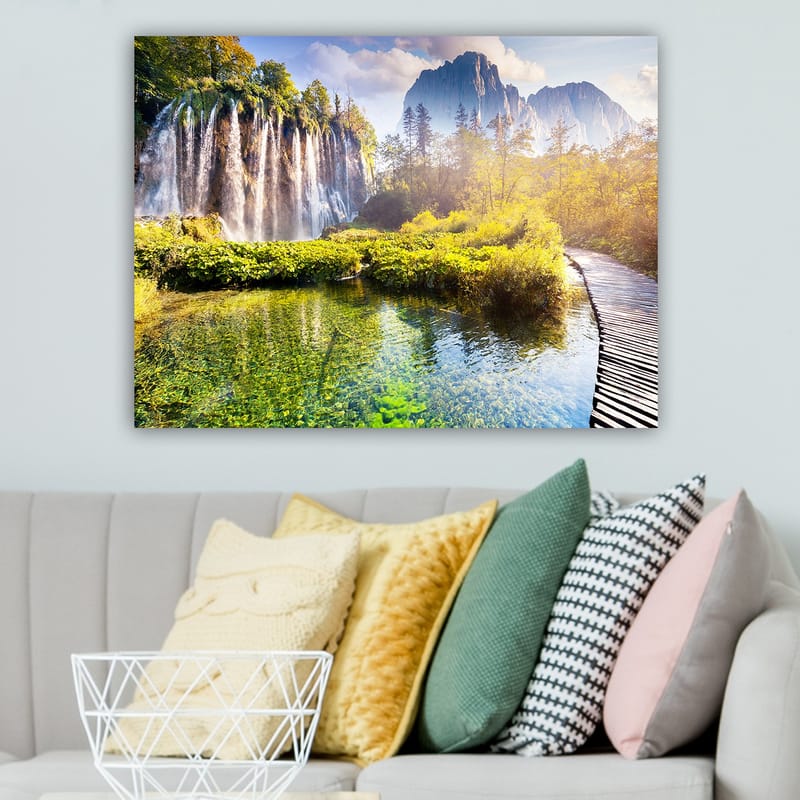 Lerretsbilde 70x100 cm - Storslått fossefall omgitt av frodig vegetasjon og majestetiske fjell - Grønn / Blå / Gul - Innredning - Bilder & kunst - Lerretsbilder