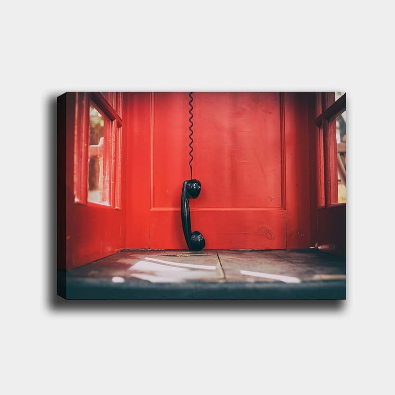 Lerretsbilde 70x100 cm - Svart telefon hengende i en rød telefonkiosk, Rød / Svart