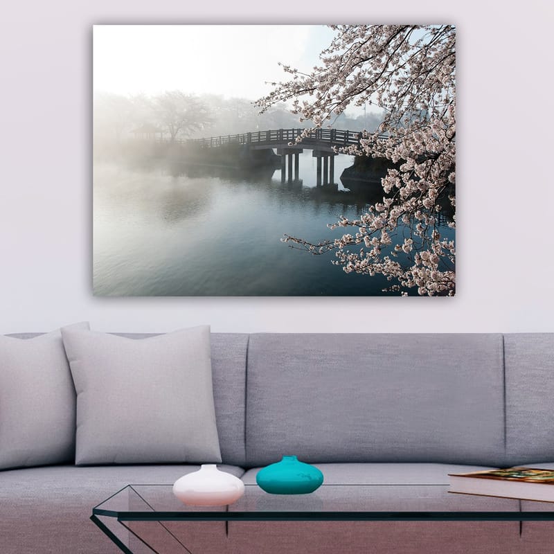Lerretsbilde 70x100 cm - Tåkete landskap med en bro som går over en stille innsjø, omgitt av blomstrende kirsebærtrær - Lys rosa / Blå / Grå - Innredning - Bilder & kunst - Lerretsbilder