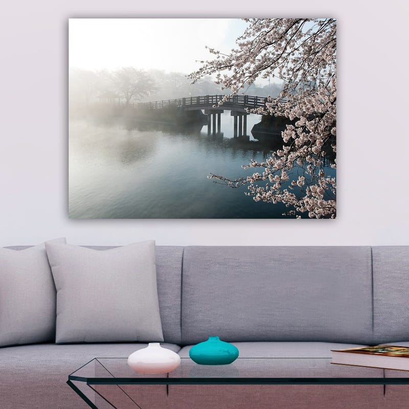 Lerretsbilde 70x100 cm - Tåkete landskap med en bro som går over en stille innsjø, omgitt av blomstrende kirsebærtrær - Lys rosa / Blå / Grå - Innredning - Bilder & kunst - Lerretsbilder
