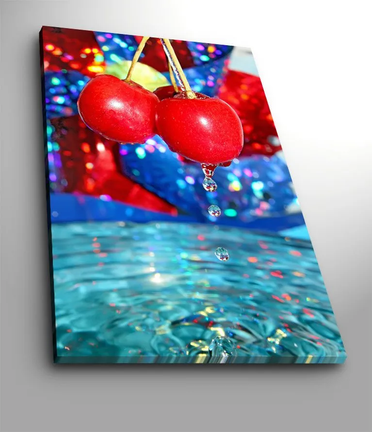 Lerretsbilde 70x100 cm - To røde kirsebær som henger over en vannflate med dr åper som faller ned, Rød / Blå / Turkis