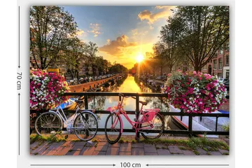 Lerretsbilde 70x100 cm - To sykler i pittoresk kanalsetting med blomster og solnedgang - Rosa / Hvit / Grønn - Innredning - Bilder & kunst - Lerretsbilder