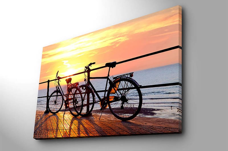 Lerretsbilde 70x100 cm - To sykler som står på en brygge ved solnedgang over havet - Oransje / Svart / Gul - Innredning - Bilder & kunst - Lerretsbilder